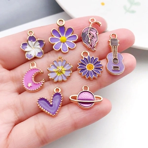 Assorted purple enamel charms in hand including flowers and moon for DIY jewelry making