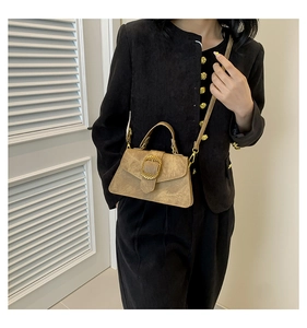 Close-up of retro brown crossbody bag featuring a golden circular buckle and matte texture