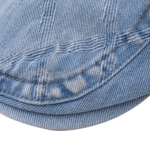 Close-up of light blue denim flat cap showing premium double stitching and washed texture