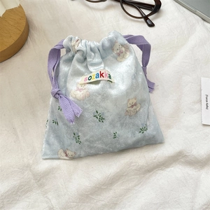 Macro detail of soft light blue velvet drawstring pouch with cute cartoon bear pattern