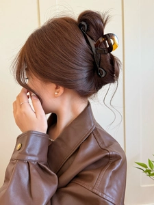 Detail of large amber tortoiseshell hair claw clip securing a chic bun on a female model