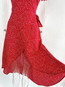 Close-up of red polka dot wrap dress featuring a v-neckline and tie-waist detail