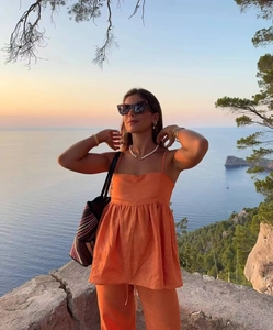 Détail d'un ensemble caraco et pantalon large en lin orange au bord de la mer au coucher du soleil