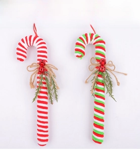 Close-up of red and white striped candy cane ornaments with pine needles and bells