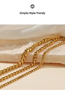 Macro shot of three gold-plated Cuban chain necklaces in varying widths on marble
