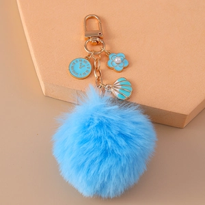 Detail of blue faux rabbit fur pom pom keychain with clock and shell charms