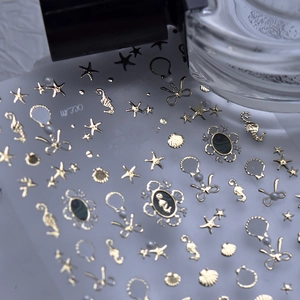 Macro view of 3D gold ocean nail stickers featuring shells, seahorses and pearls