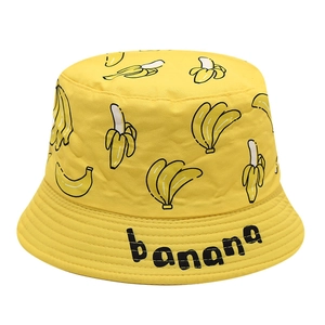 Gros plan d'un chapeau de soleil jaune en coton avec motifs bananes et logo stylisé