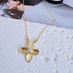 Macro shot of gold four-leaf flower necklace with elegant white pearl center detail