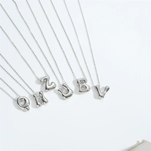 Close-up of polished silver balloon letter pendants Q N Z J B V on delicate chains