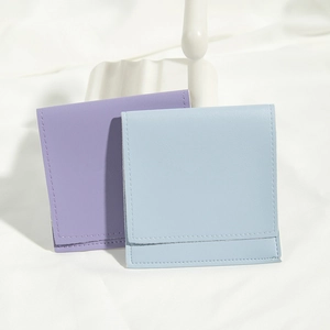 Close-up of soft purple and light blue faux leather jewelry pouches on white fabric