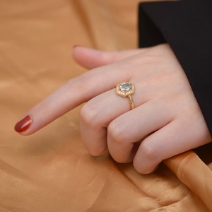 Close-up of golden S925 silver ring with hexagonal blue topaz stone on silk