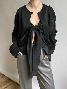 Detail of elegant black satin top featuring a large bow tie and backless design