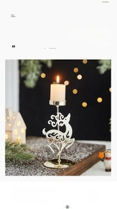 Close-up of a festive golden metal elk candle holder with a white pillar candle on wood