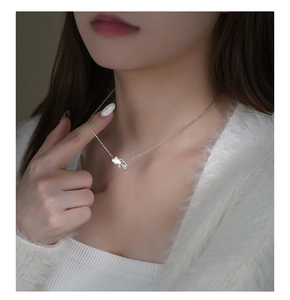 Close-up of cloud-shaped sterling silver pendant on a delicate chain around a neck