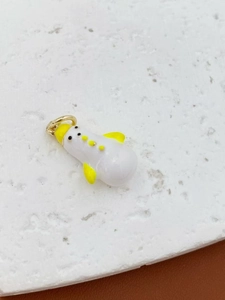 Macro detail of cute snowman pendant with enamel finish and yellow hat for bags