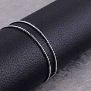Macro shot of silver stainless steel round snake chain on a black leather stand