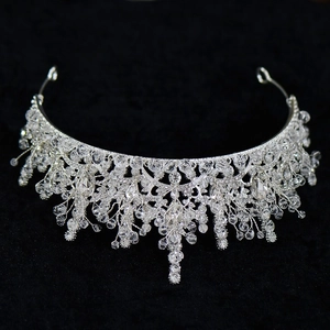 Detailed close-up of sparkling crystal bridal crown with dangling tassels on black velvet