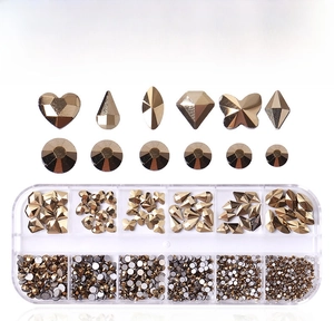 Detail of 12-grid box with golden crystal nail art rhinestones and assorted shapes