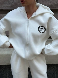 Close-up of white hooded zip-up tracksuit featuring a black crown logo and drawstring detail