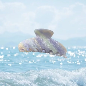 Pince à cheveux en acétate marbré aux rayures pastel sur fond de vagues de l'océan
