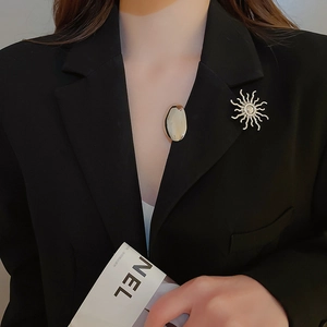 Close-up of silver sunflower brooch and geometric pin on a black suit lapel