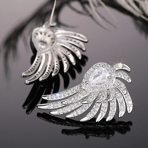 Macro shot of silver wing earrings with shimmering micro-pave diamonds and pear-shaped stones