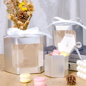 Detailed view of silver hexagonal window gift boxes with white ribbons and macaron display