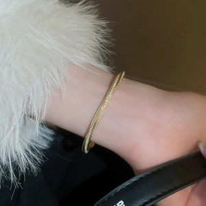 Macro shot of gold-plated twisted bracelet featuring shimmering pave-set zircon stones