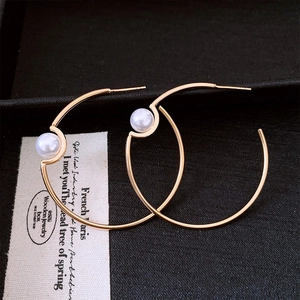 Close-up of gold-plated C-shaped hoop earrings with elegant pearl inlay and minimalist style
