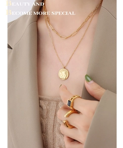 Detail of layered gold angel pendant necklace and rings styled with a blazer
