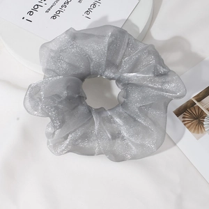 Close-up of silver-gray organza scrunchie with shimmering glitter texture and sheer fabric