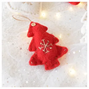 Detail of red wool felt Christmas tree ornament with twine snowflake and button