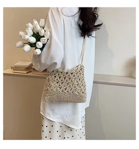 Detailed close-up of beige straw crossbody bag featuring hollow floral crochet patterns