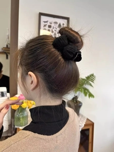Close-up of black knitted bow hair claw clip securing a bun hairstyle for women