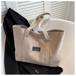 Flat lay of beige canvas tote bag with black blazer, showcasing minimalist commuter style