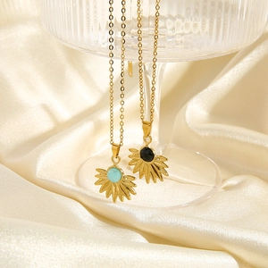 Detail of sunburst fan necklaces with green and black stone insets on a gold chain