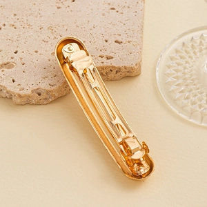 Detailed back view of golden metal hair clip showing the durable spring mechanism