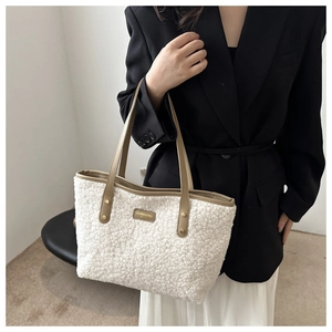 Detail view of cream plush tote bag featuring faux fur texture and brown leather trim accents