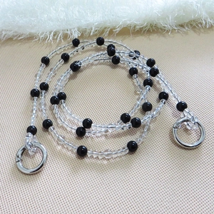 Detail of black and transparent beaded bag strap with silver metal ring clasps