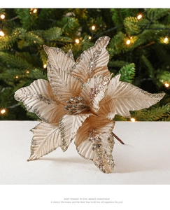 Vue détaillée d'un poinsettia pailleté or champagne sur un sapin de Noël aux tons chauds