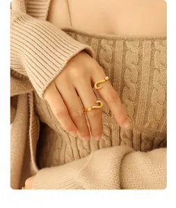 Detail of two gold question mark rings with a matte finish on model's hand