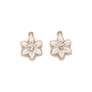Detail of white enamel flower charm with golden border and central sparkling rhinestone