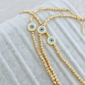 Macro shot of 18K gold plated beaded Evil Eye bracelet with blue enamel detail and lobster clasp