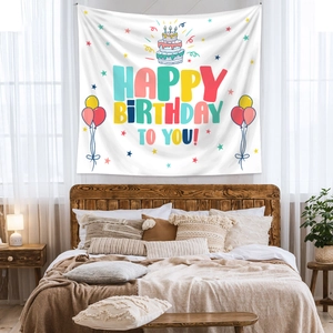 Close-up of bohemian Happy Birthday tapestry with cake and balloon patterns on a cozy bed