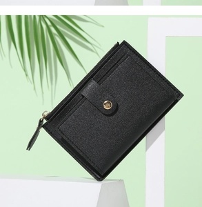 Close-up of black litchi pattern leather wallet with gold hardware on white pedestal