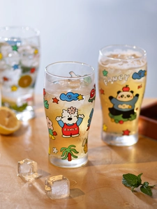 Close-up of glass cups with cartoon bear patterns and FANCY text on wooden table