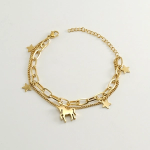 Détail d'un bracelet doré à double chaîne orné de pendentifs étoile et licorne