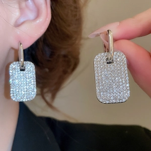 Dettaglio degli orecchini a cerchio quadrati argentati con micro-pave di cristalli sul modello
