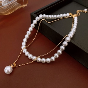 Gros plan d'un collier double épaisseur plaqué or avec perles blanches et pendentif
